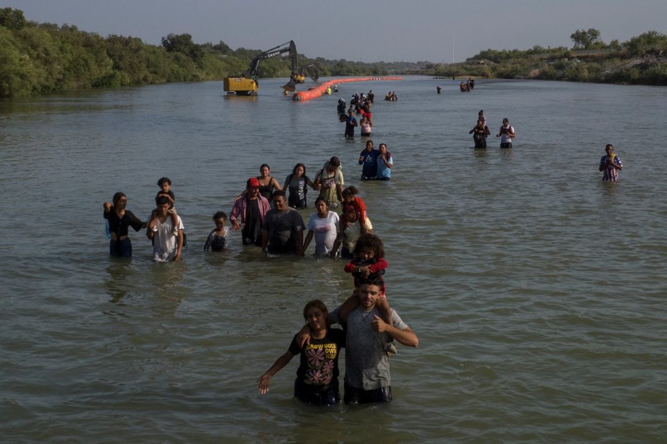 Běženci v řece Rio Grande se brodí kolem bójí,  které je mají odradit od překročení hranice mezi USA a Mexikem | foto: Adrees Latif,  Reuters